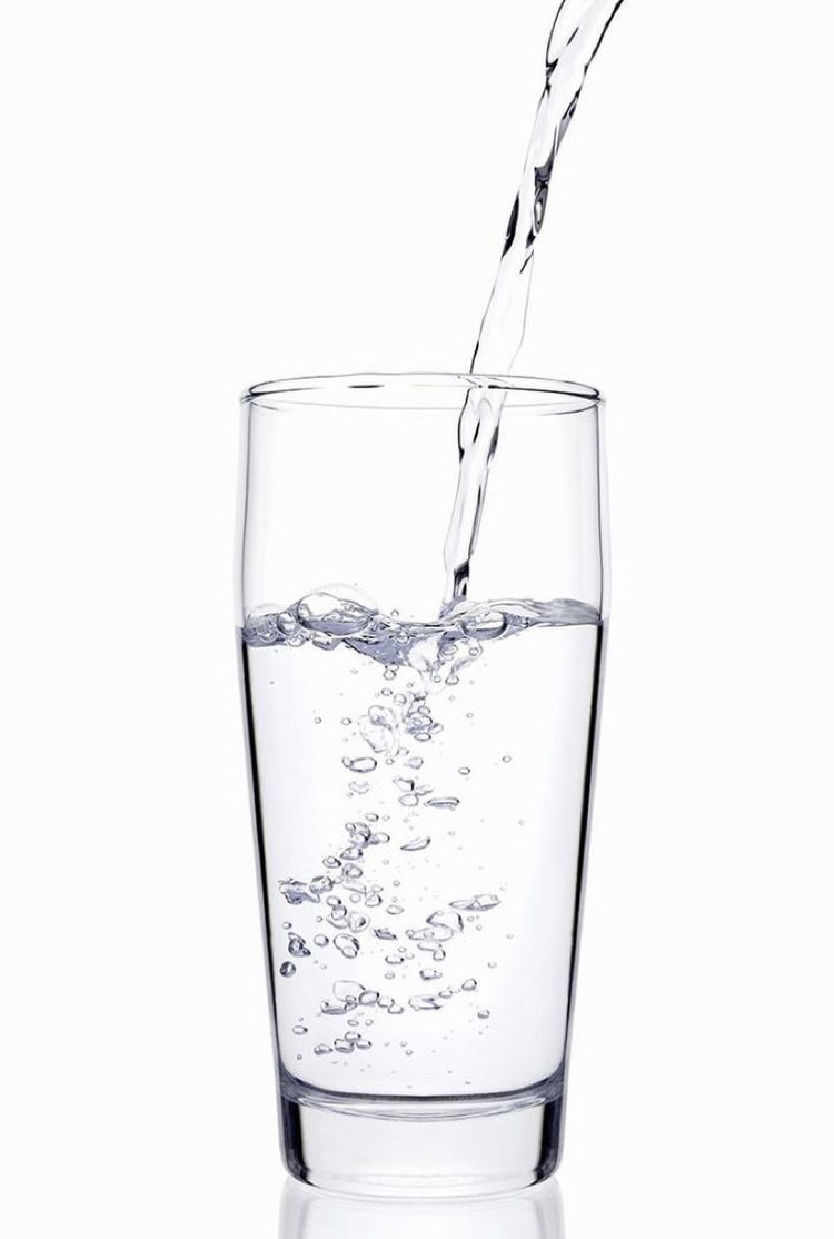 A glass of water on a table, representing hydration, health, and overall wellness.